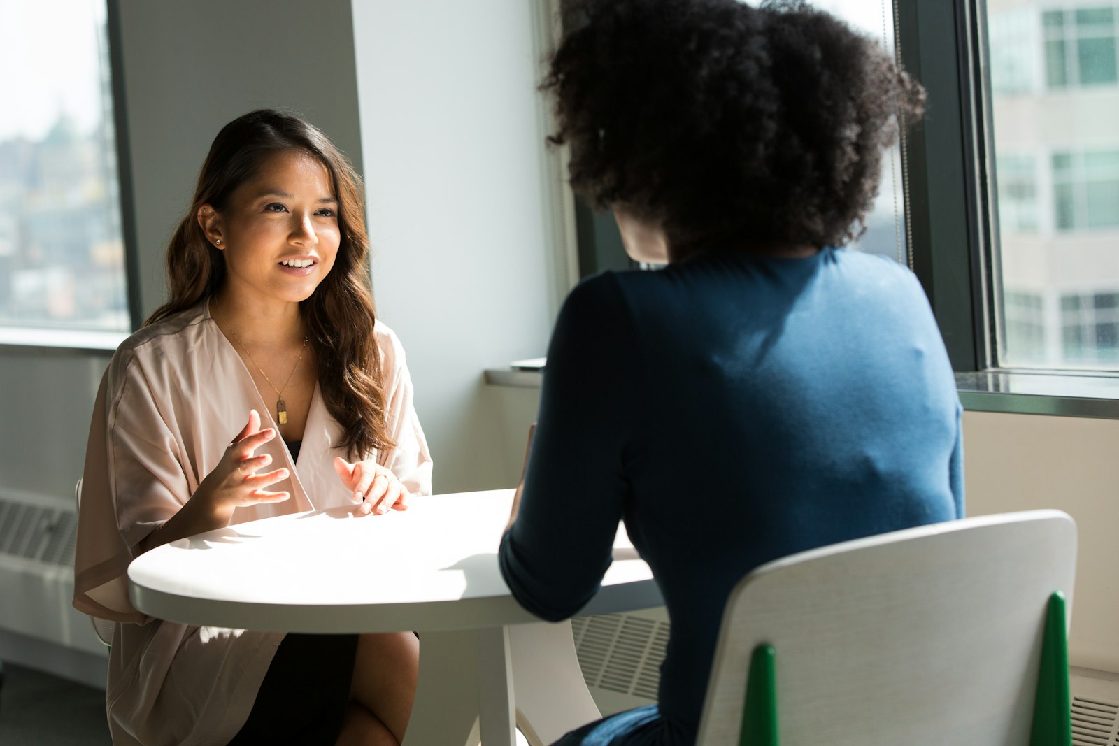 Two professionals in conversation at an office table, the kind of scoping conversation a first call with Avisha Global looks like