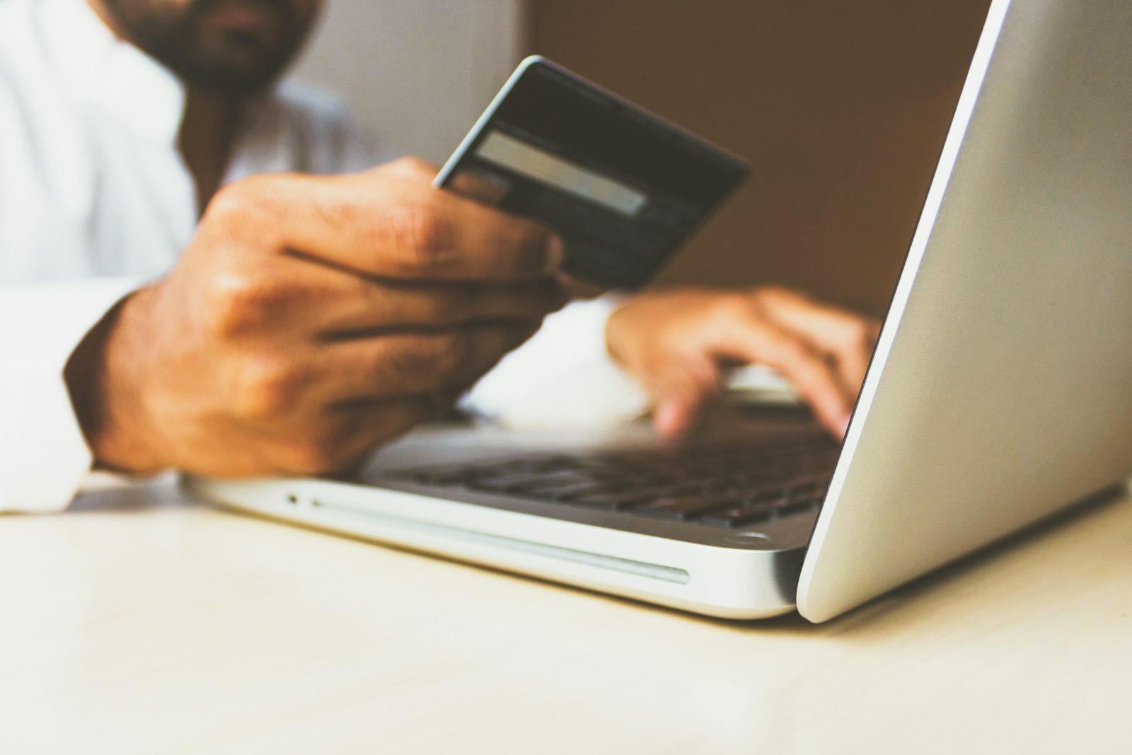 Hand holding a payment card at a laptop — consent captured at the point of collection